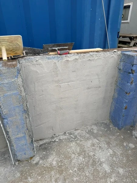 Rendered panel on a blockwork section with tools resting on the top edge