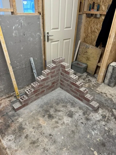 Small stepped brick corner build on a workshop floor during bricklaying training
