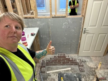 Trainee giving a thumbs up with a brick corner build in the background
