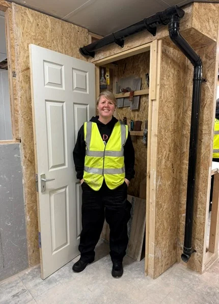 Standing by a fitted door frame with guttering and downpipe installed above