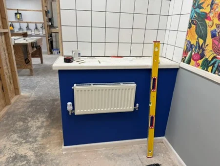 Radiator installed on a training bay wall with a spirit level beside it