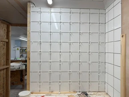 White tiled wall fitted with spacers and tile levelling clips