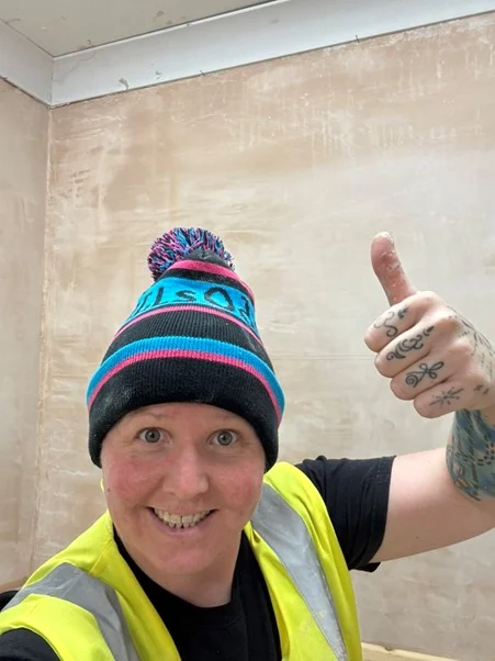 giving a thumbs up in front of a freshly plastered wall